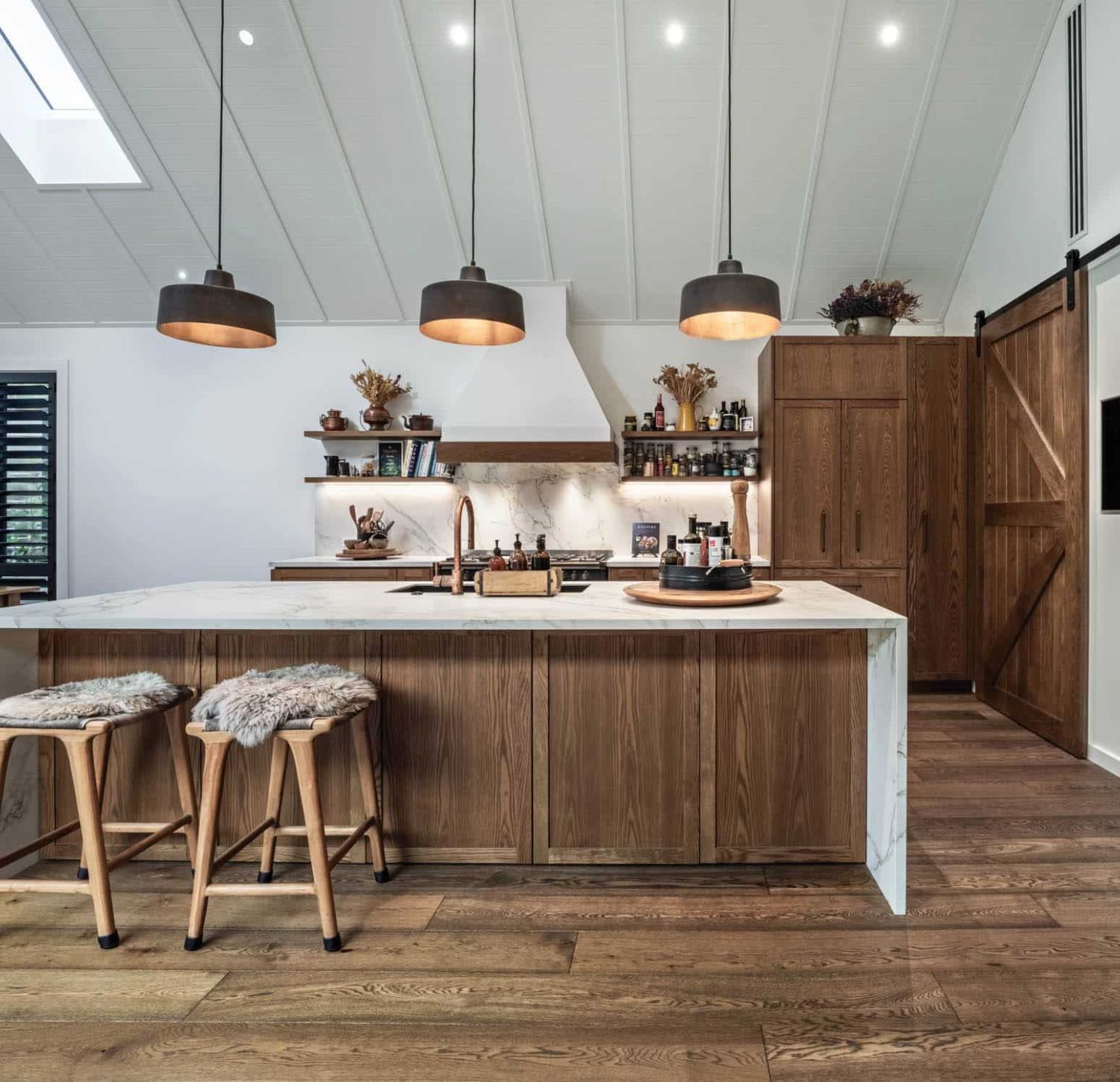 Rural home kitchen with raked timber ceiling, oak island, barn door and pendant lighting – Chilton + Mayne architectural designers